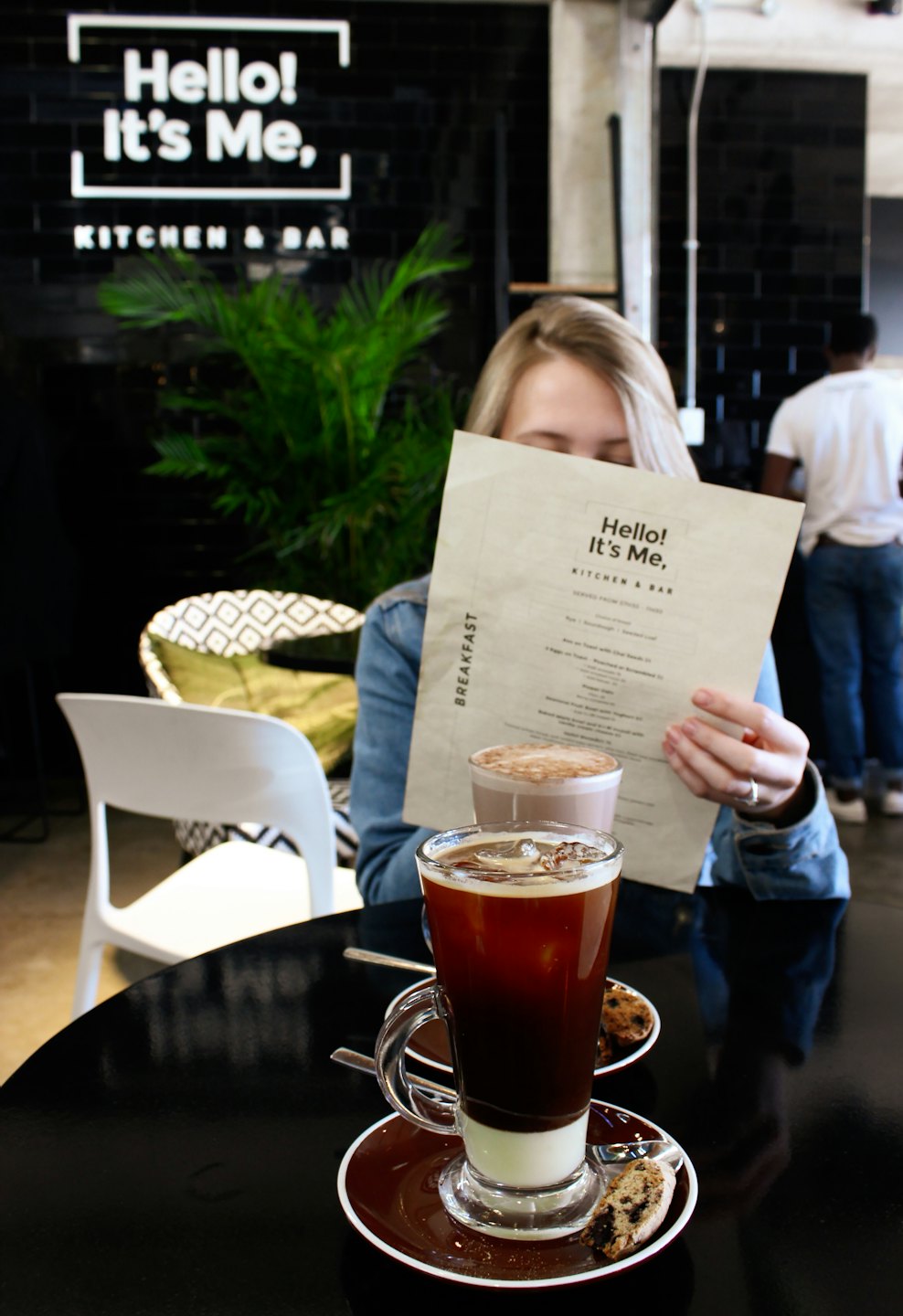 Person reading a menu at a table with two drinks.